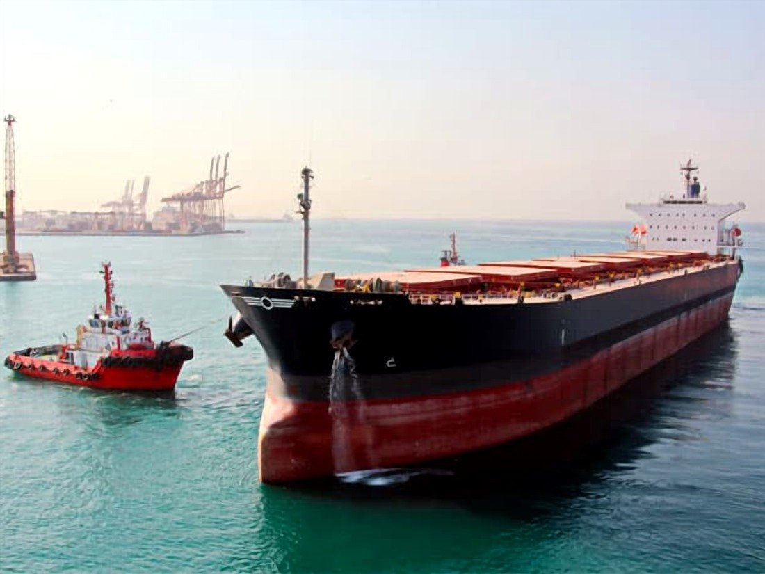 Bulk carrier with tug at port, the full vessel assessed in a pre-purchase survey